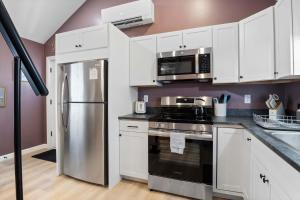 a kitchen with white cabinets and a stainless steel refrigerator at Coastal Breeze Cottage - Tiny Home at Hampton Beach in Hampton