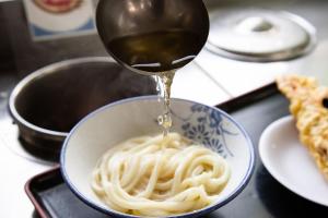 Eine Schüssel Pasta, die mit Soße beträufelt wird. in der Unterkunft HOTEL MYTH-S -ホテル マイス エス- adult only in Sakaide