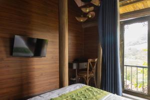 a bedroom with a bed and a tv on a wall at Bamboo Hill Resort in Hữu Lũng