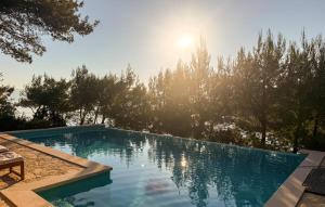 a swimming pool with the sun shining through the trees at Villa Aqua in Vrbanj