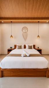 a bedroom with a large white bed with two lights at The Tamarin Villas in Nusa Penida +36 photos