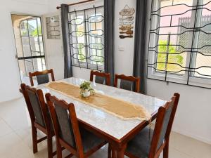 a dining room with a table and chairs and windows at The Beloved Corner in Nausori