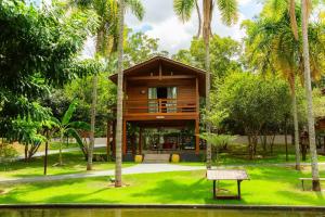 a wooden house in a park with palm trees at Chalé dos Lagos Ecoresort in Mandaguaçu