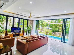 a living room with couches and a television and a pool at Danang Villas Complex in Danang