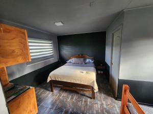 a bedroom with a bed in a black room at Cabañas Kai Rau Tu in Hanga Roa