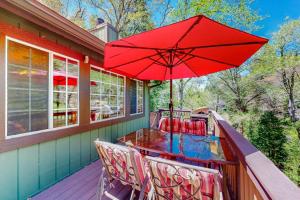 a table and chairs on a deck with a red umbrella at Creekside Cabin in Crestline