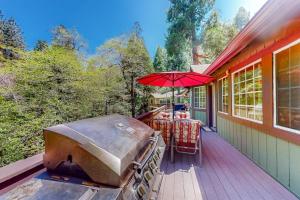 a bbq on a deck with a table and an umbrella at Creekside Cabin in Crestline +24 photos