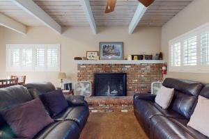 a living room with a leather couch and a fireplace at Dancing Bear Chalet in Lake Arrowhead