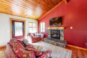 a living room with a red wall with a fireplace at Sky High Cabin in Crestline