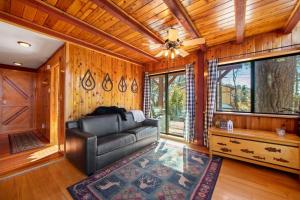 a living room with a leather couch and wooden walls at The Valley's Cabin in Green Valley Lake