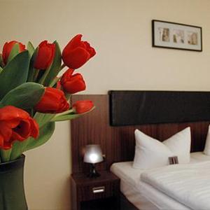 a vase filled with red tulips in a bedroom at City Hotel Mercator in Frankfurt/Main