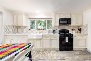 a kitchen with white cabinets and a black stove at Top Town Retreat in Crestline +14 photos