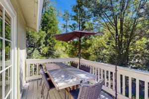 a wooden table and chairs on a porch with an umbrella at Treetop Cottage in Running Springs