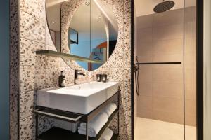 a bathroom with a sink and a mirror at Me and All Hotel Leipzig, by Hyatt in Leipzig