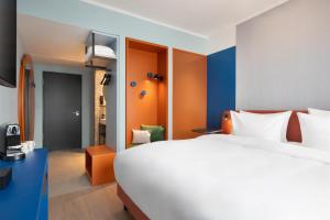 a hotel room with a large white bed and orange accents at Me and All Hotel Leipzig, by Hyatt in Leipzig