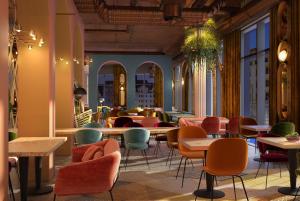 a restaurant with colorful chairs and tables in a room at Me and All Hotel Leipzig, by Hyatt in Leipzig