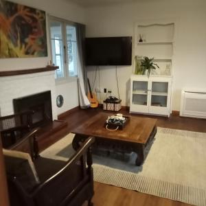 a living room with a coffee table and a flat screen tv at Dated but Delightful on D'Arcy in Richmond
