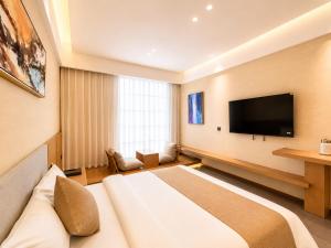 a hotel room with a bed and a flat screen tv at Clover Hotel & Spa in Phnom Penh