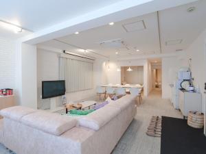 a living room with a large couch and a table at INOVE VILLA OSAKA -120m2 , 7 Double Beds , 2 BR , 2 Bath , Easy Access to Umeda , Kyoto ーPerfect for Families & Groupsー in Osaka