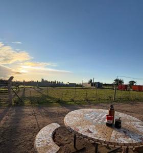 a table with a bottle on it sitting in a field at Alojamiento Caroya in Colonia Caroya