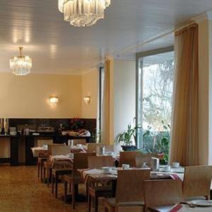 ein Restaurant mit Tischen, Stühlen und einem Kronleuchter in der Unterkunft City Hotel Mercator in Frankfurt am Main