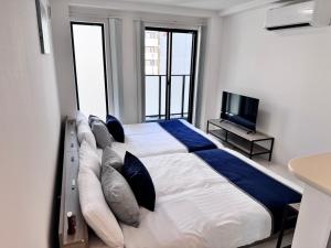 a bedroom with a large bed with pillows and a tv at LIFEMENTGLANZ HOTEL Enomachi in Hiroshima