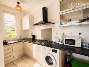a kitchen with a washing machine and a microwave at Petit Havre de Paix BIS - Piscine et plage à pied in Le Gosier