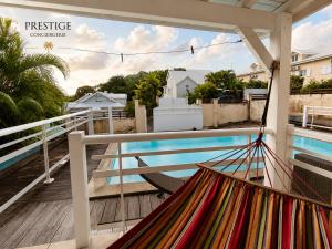 a hammock on a balcony overlooking a swimming pool at Petit Havre de Paix BIS - Piscine et plage à pied in Le Gosier