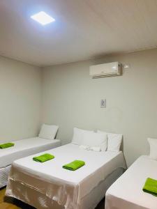 a room with two beds with green towels on them at Chalé Brisa da Lagoa in Icaraí