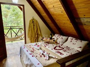 a bedroom with a bed with red flowers on it at Chalé Suíço - Chalés Belo Monte - Sítio Belo Monte in Pacoti +41 photos