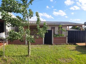 a house with a small tree in the yard at Casa con piscina en Gobernador Roca in Gobernador Roca