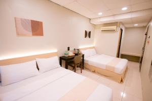 a hotel room with two beds and a desk at Rovers Hotel Kubang Kerian in Kota Bharu