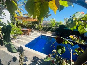 a swimming pool in a yard with a table and an umbrella at Sunsets at Sumbul in Pulukan