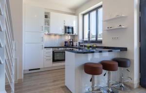 a kitchen with white cabinets and a counter with stools at Amber in Binz