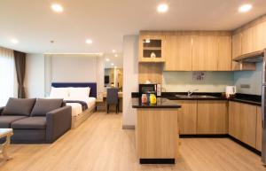 a hotel room with a bed and a couch and a kitchen at Chaidee Mansion in Bangkok