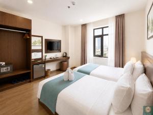 a hotel room with two beds and a television at Corner Central Danang City Hotel in Danang