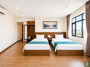 a hotel room with two beds and a window at Corner Central Danang City Hotel in Danang
