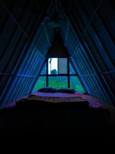 a bed in a blue tent with a window at Vagamon leafmist frame cabin in Vagamon