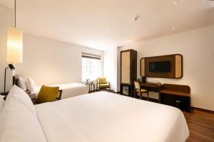 a hotel room with a white bed and a desk at Pavilion Essence Hanoi Hotel in Hanoi