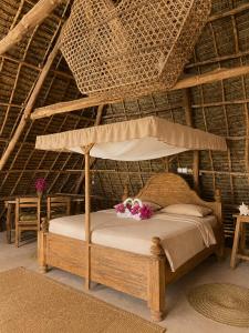 a bed with a canopy in a straw hut at Kita Ocean House in Kiwengwa