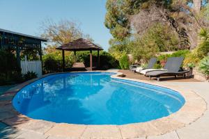 a swimming pool with chairs and a gazebo at Lanterns Retreat in Dunsborough