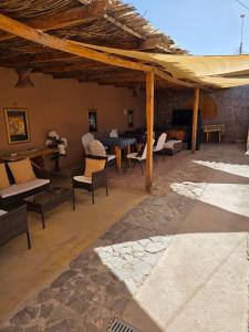 a patio with chairs and tables and a stone wall at Hostal Desert in San Pedro de Atacama