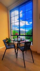 a table and two chairs in front of a large window at Mumbai SkyLine Luxury Suite in Quito