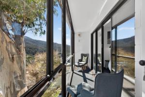a room with windows and chairs looking out at the mountains at Tyrola 11 in Thredbo