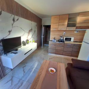 a living room with a television and a table at къщички Поляните in Sinemorets
