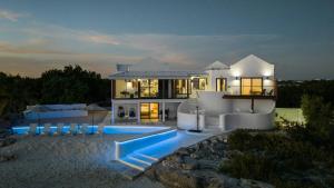 a large white house with a swimming pool at night at Opaline Villa 4BR 2Bath-Ocean Front in Providenciales
