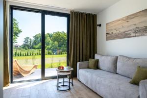 a living room with a couch and a sliding glass door at Ostoja Lubiatowo in Lubiatowo