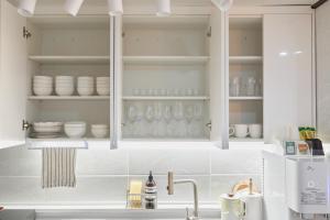 a kitchen with white cabinets and plates and glasses at Stay GAON in Seoul +101 photos