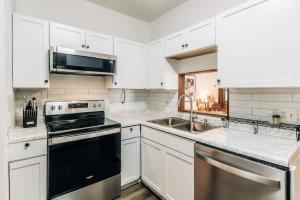a kitchen with white cabinets and a stove and a sink at Minnehaha Falls Hideaway in Minneapolis
