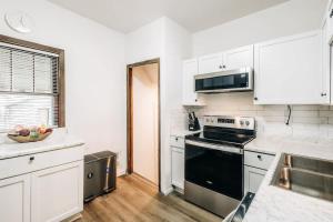 a kitchen with white cabinets and a black stove top oven at Minnehaha Falls Hideaway in Minneapolis +21 photos